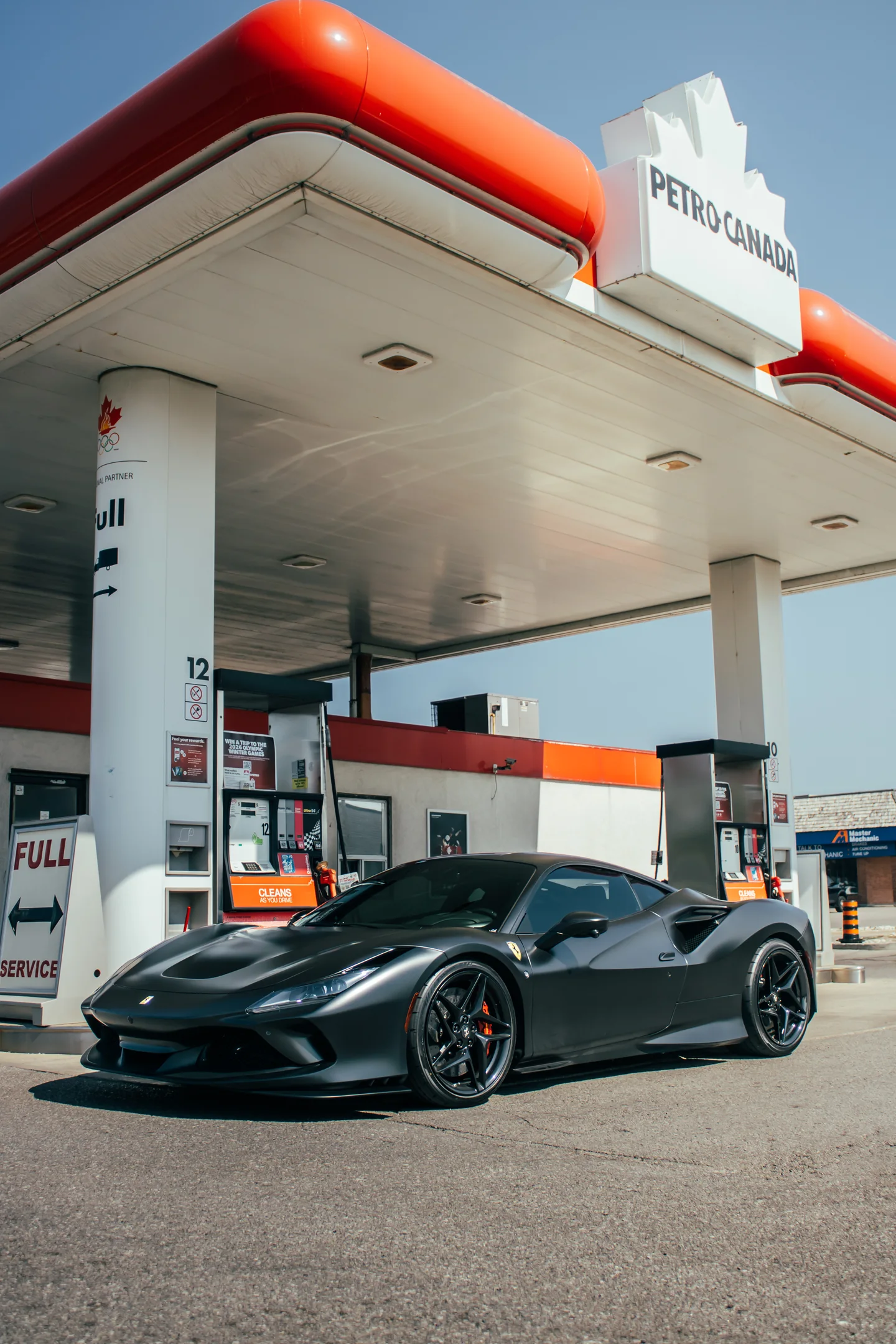 A black Ferrari F8 Tributo pulled up under a Petro-Canada canopy.