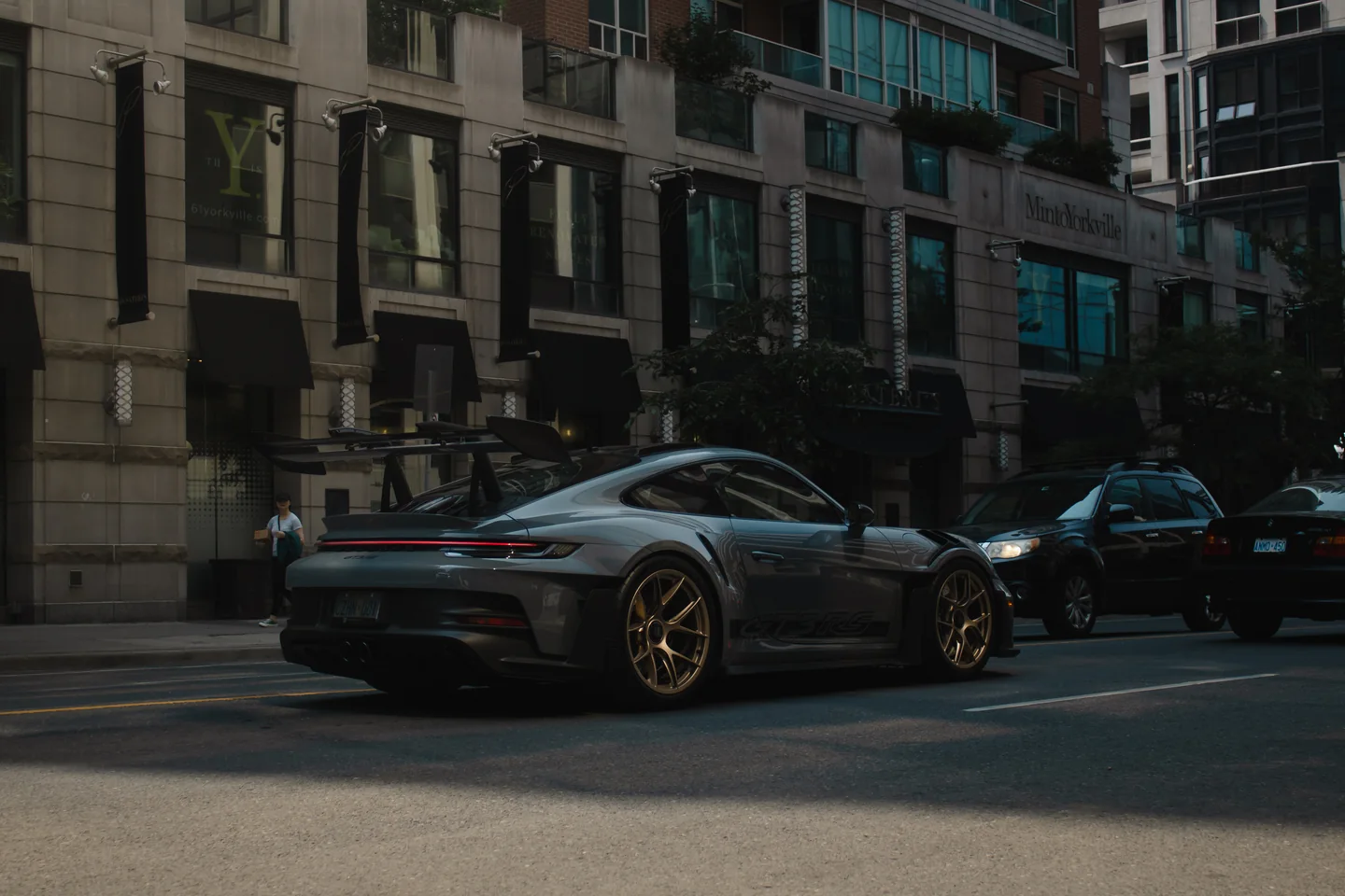 A grey Porsche 911 GT3 RS parked low on a downtown Toronto street with condo towers rising behind it.