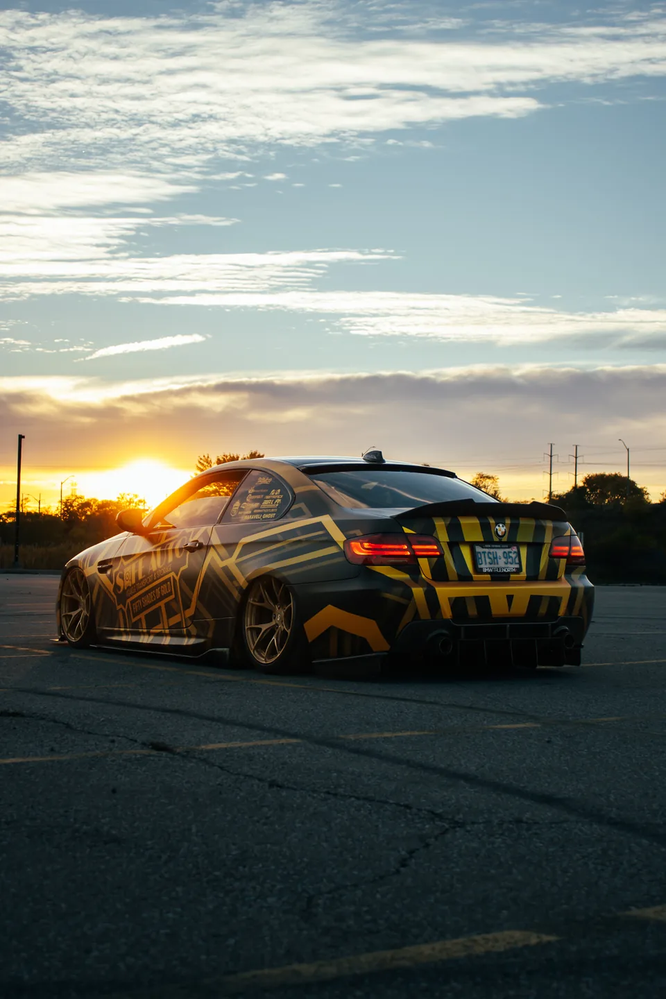 A liveried car rear three-quarter as the sun drops behind an empty lot.