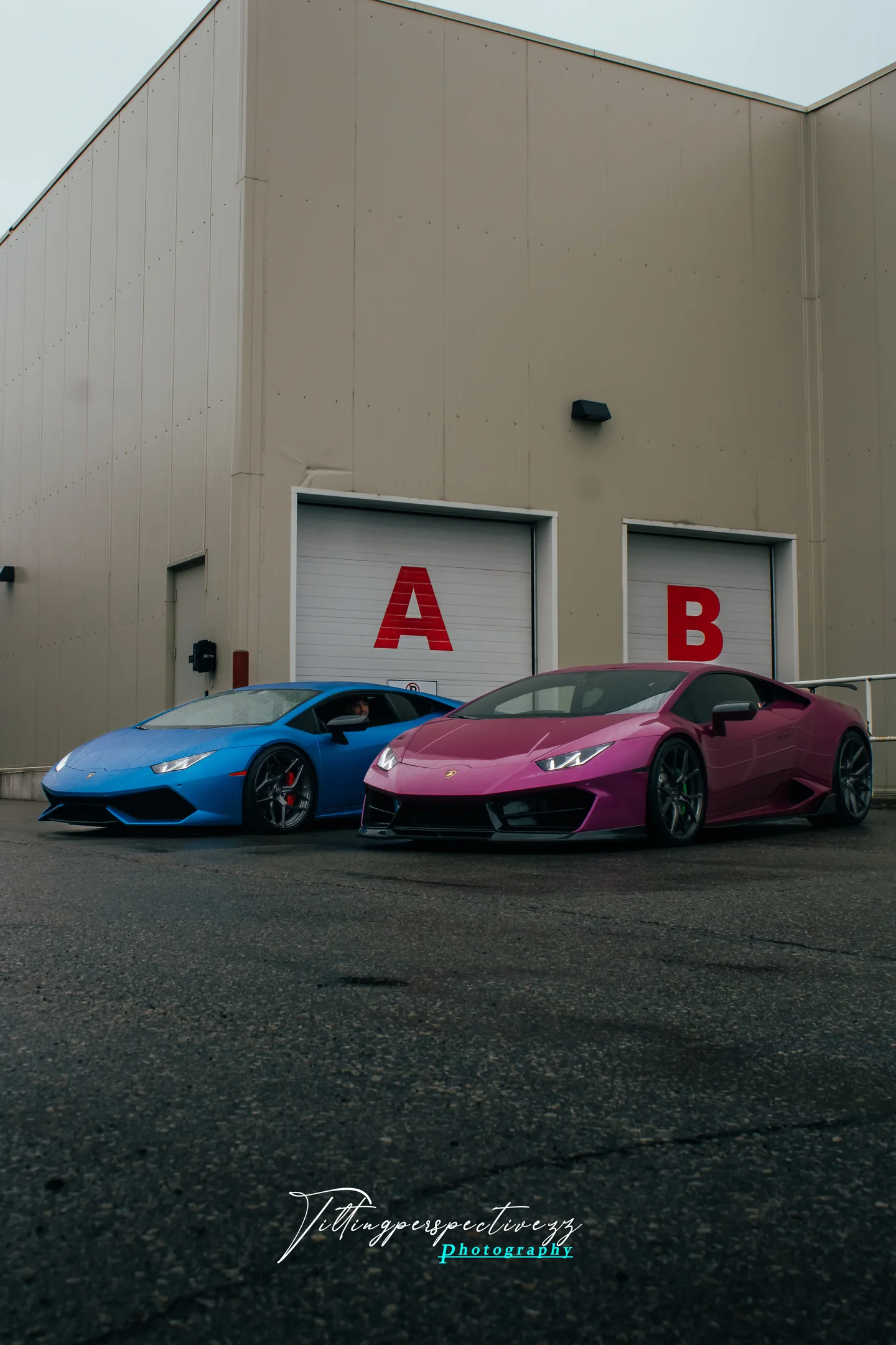 A blue and a pink Lamborghini Huracan parked in front of lettered garage doors at the Autostrada season opener.