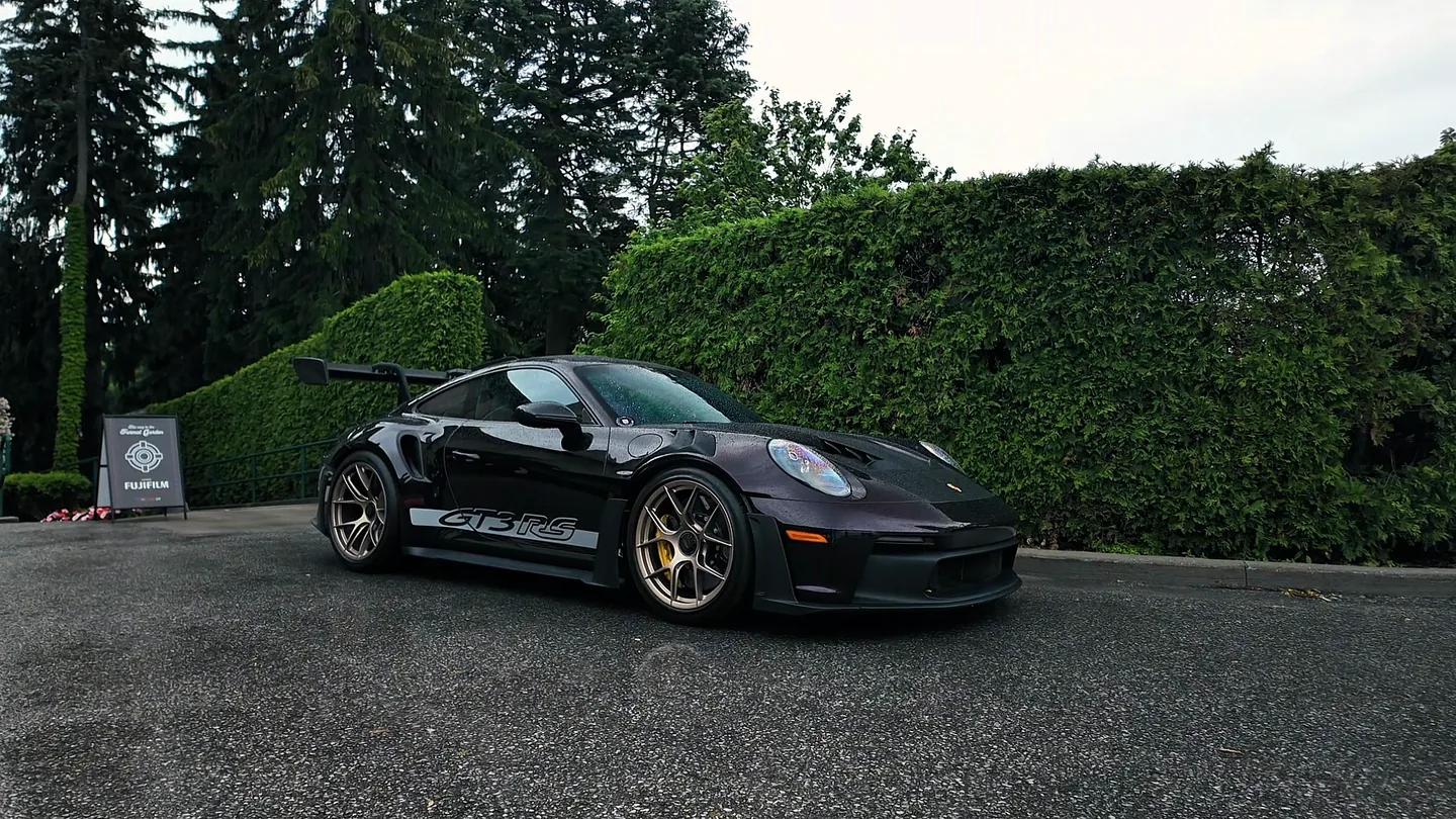 Walking through a Porsche meet on a wet morning, cars parked along the gravel drive of a stone estate.